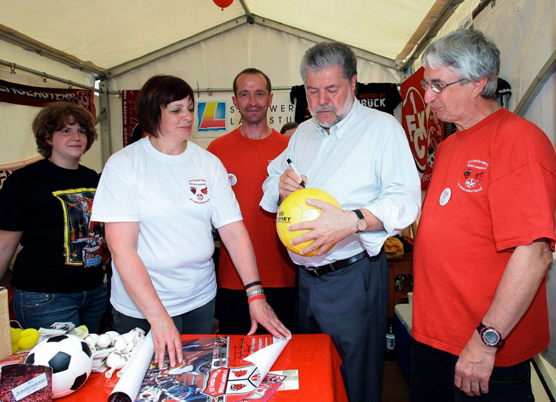  Ministerpräsident Kurt Beck besuchte den Fairplay-Stand in Neustadt/Weinstraße und unterschrieb dabei einen Fußball zur Erinnerung an den „Rheinland-Pfalz-Tag 2010“ (Foto: Staatskanzlei).